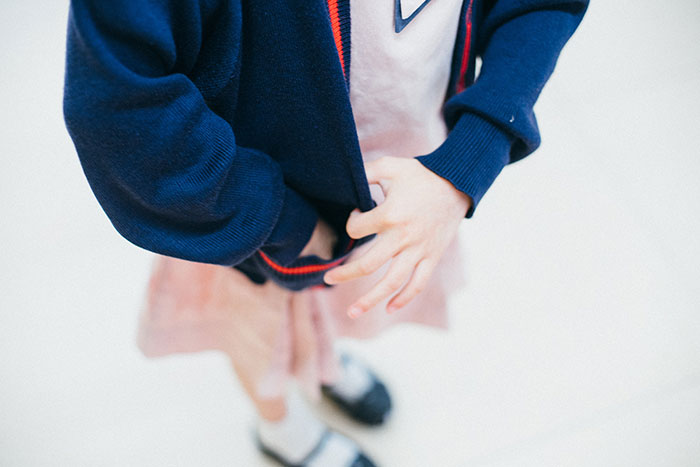 Girl tugging her blue school jacket