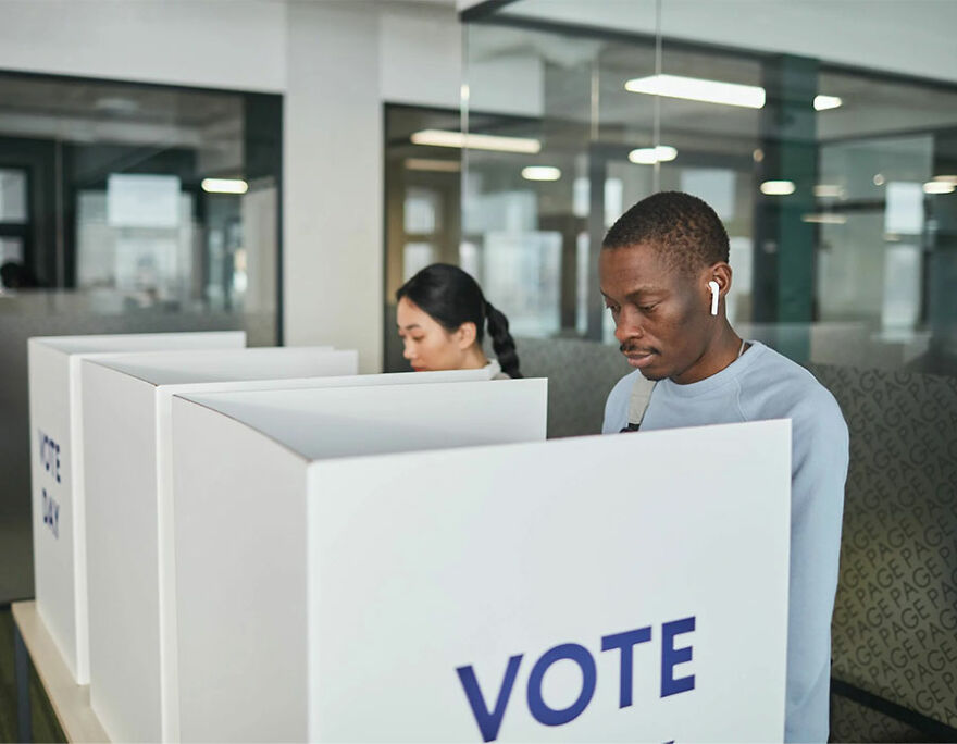 Black man and Japanese woman voting in voting booths