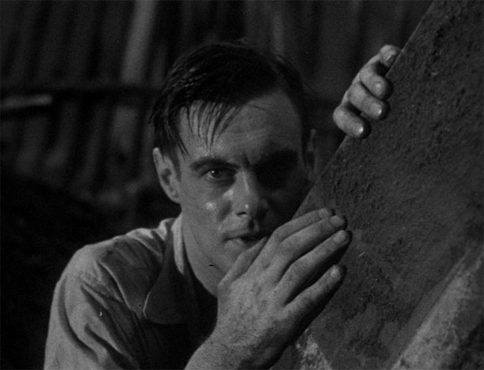 Colin Clive hiding behind a wall in the dark 