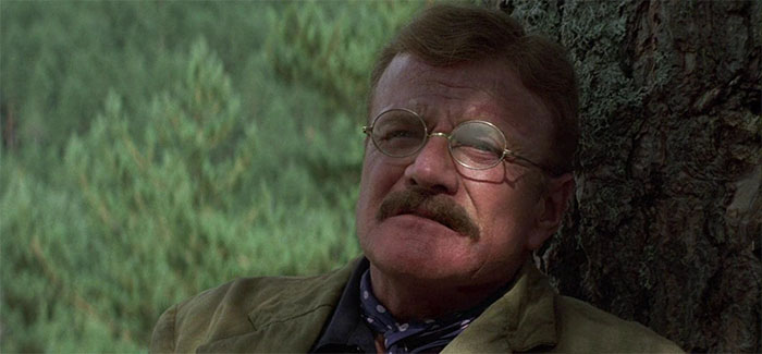 Brian Keith sitting next to a tree 