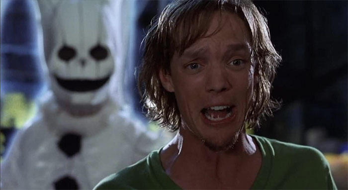 Matthew Lillard looking scared and a ghost behind him 