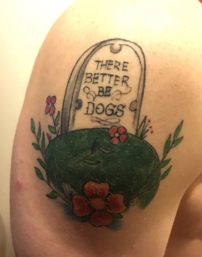 Funny tattoo featuring a tombstone with "There better be dogs" text, adorned with colorful flowers.