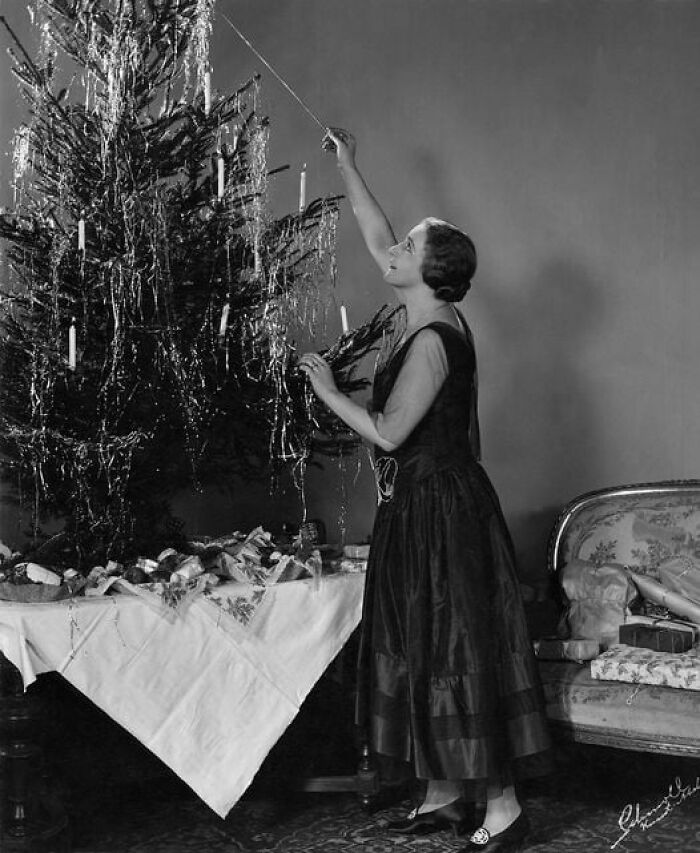 A Woman Lights The Candles On Her Christmas Tree In The 1920’s In Us