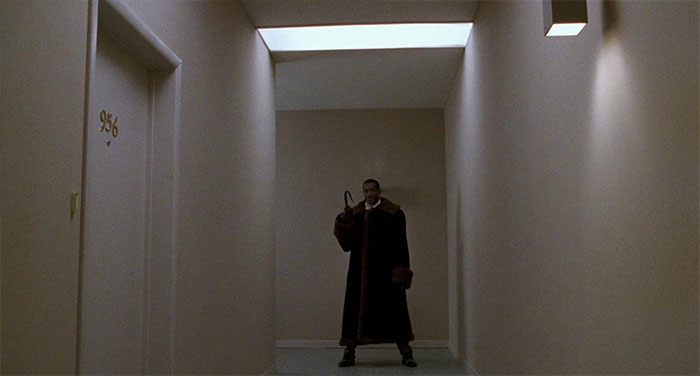 The Candyman holding an umbrella standing in the hallway 