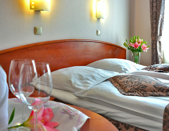 Bed with flowers and glasses near in hotel