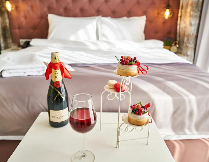 Champagne on the table with sweets near bed in hotel room