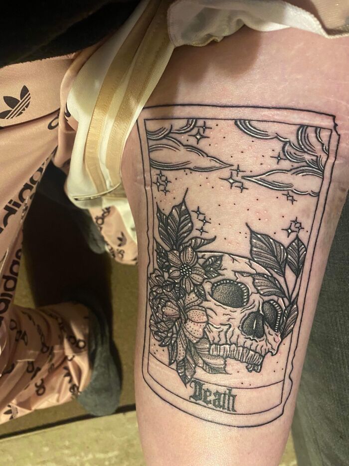 A skull and floral tattoo with stars on a person's leg, featuring intricate line work.