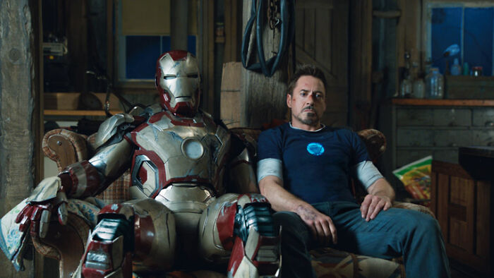 Actor Robert Downey Jr. sitting next to Iron Man suit in a rustic room, representing highest-paid actors.