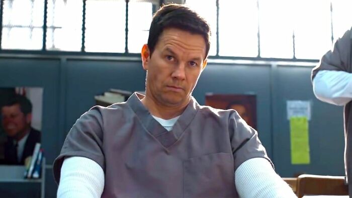 Actor in gray prison uniform sitting with arms crossed, representing one of the highest-paid actors of all time.