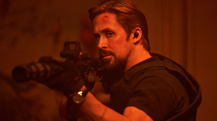 Actor aiming a rifle in a dark setting, representing one of the highest-paid actors in an intense action scene.
