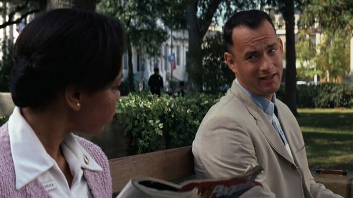 Two actors sitting on a park bench during a conversation in a scene featuring highest-paid actors in film history.