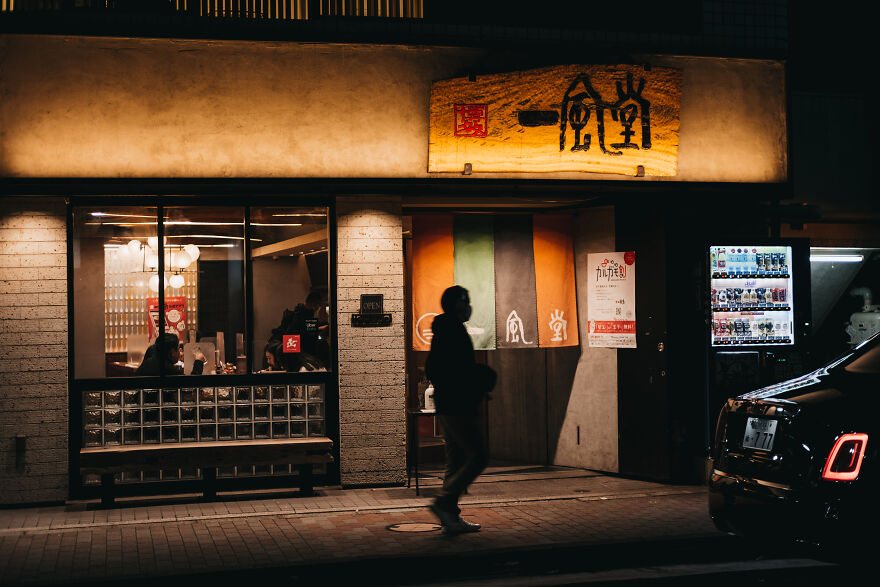 Shadowed Stride: Silhouette Navigates Tokyo's Warm, Nocturnal Hues