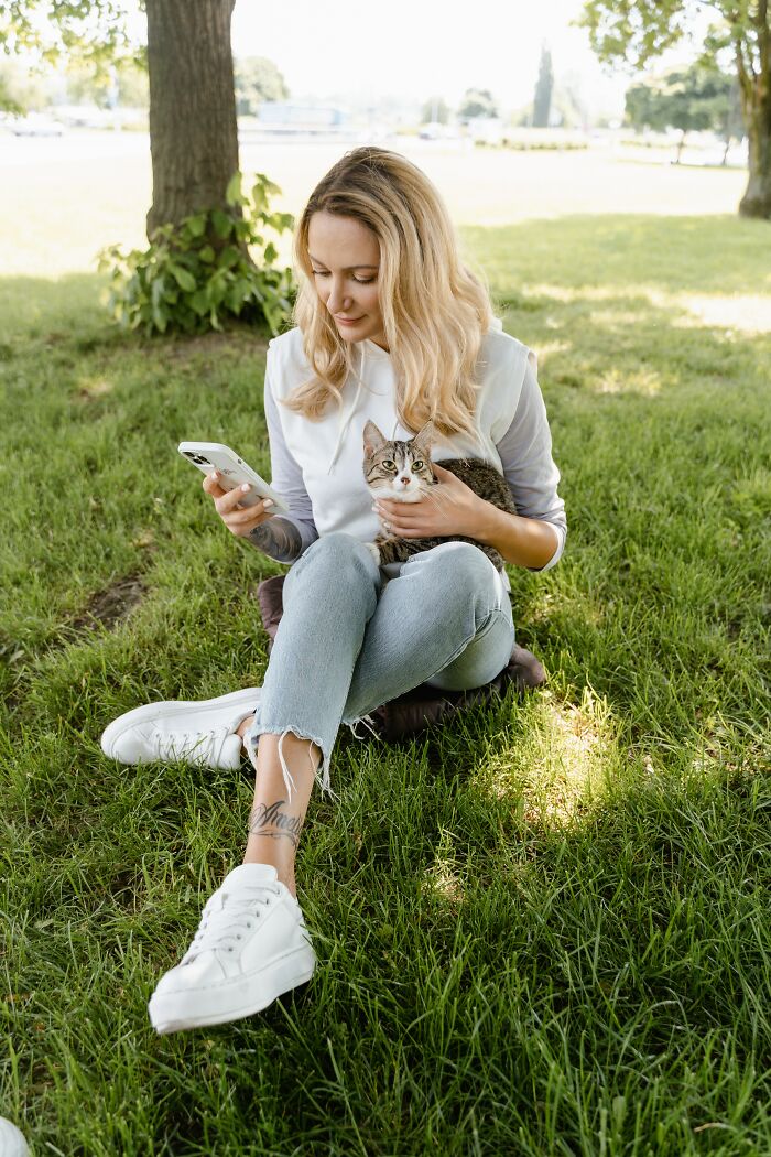Woman Sitting And Holding A Cat In The Park 