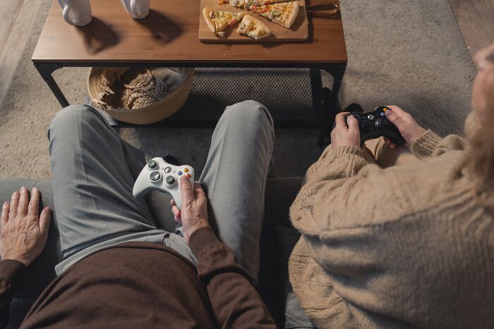 Persons sitting and holding gaming controllers