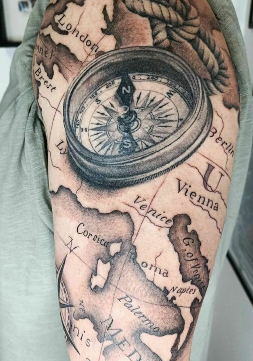 Realistic tattoo of a compass on a map, showcasing intricate detailing and artistry.