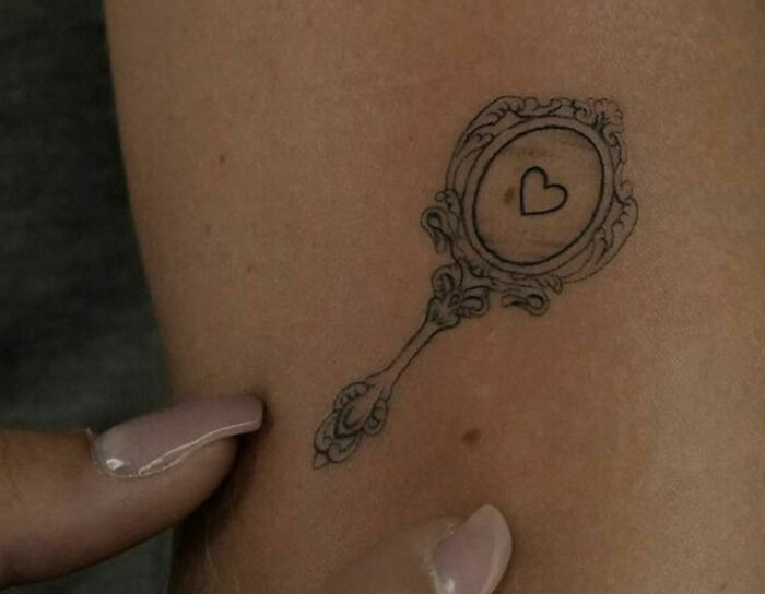 Mirror with heart inside arm tattoo
