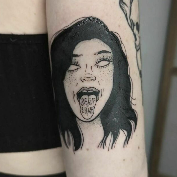 Self-love tattoo of a woman's face with "self love" written on her tongue, showcasing empowerment and deep meaning.