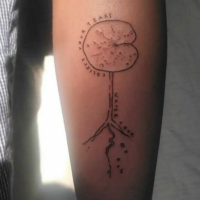 Minimalist self-love tattoo with plant roots and motivational text on an arm.