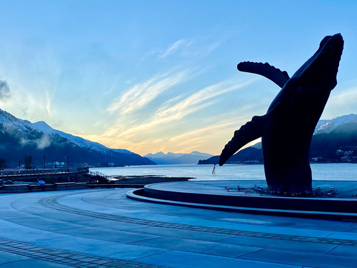 A statue of a whale in front of a body of water