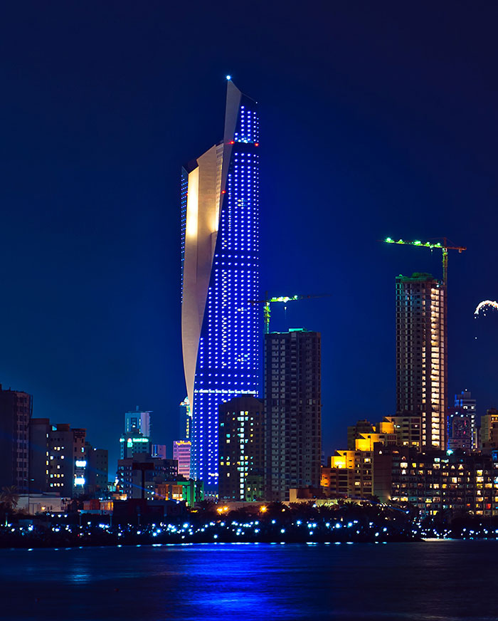 Picture of Al Hamra Tower at night near other buildings