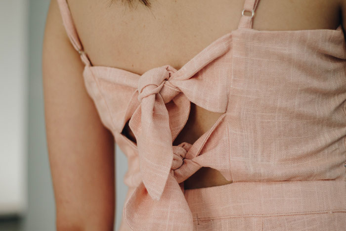 A close-up view of a woman's back wearing a pink linen outfit