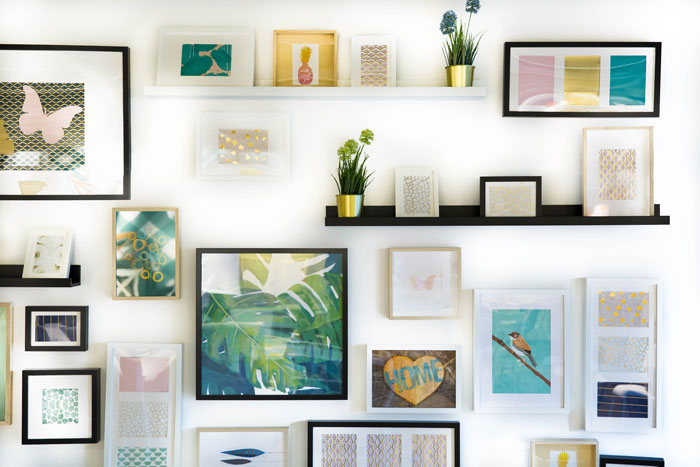 Many framed pictures on wall and on shelves