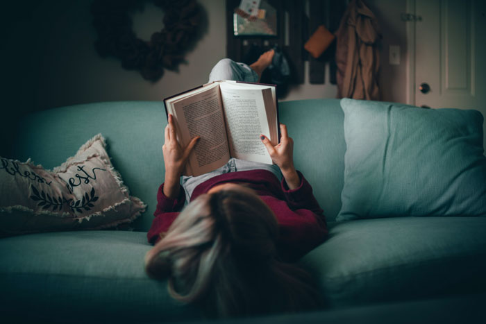 Woman lying on sofa and reading book