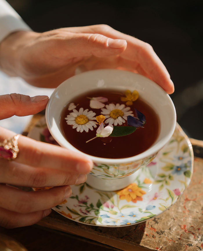 A person lifting a cup of chamomile tea