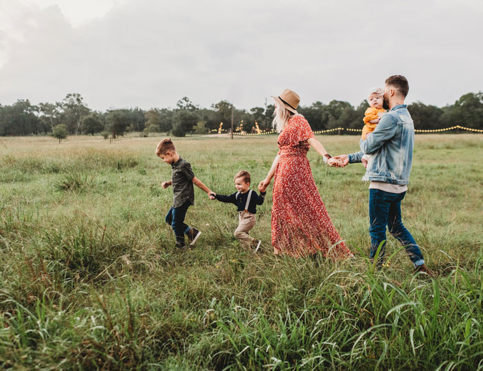 Five-person family is holding hands and walking in the field