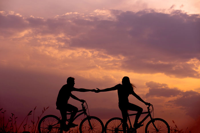 Couple riding bikes and touching each other hands