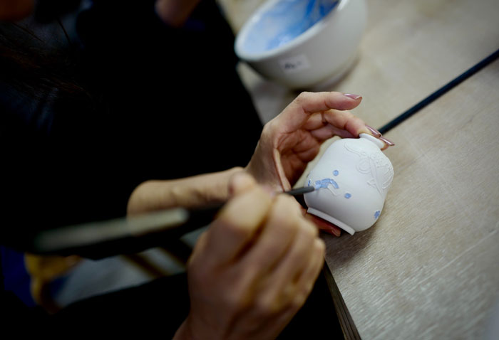 Woman coloring a little white vase