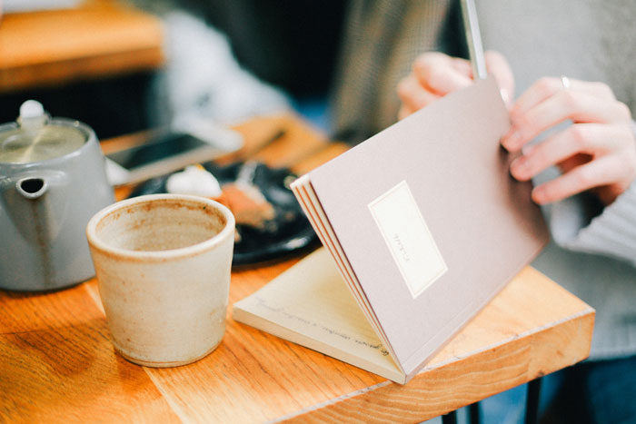 A woman sitting near the table and writing in a notebook