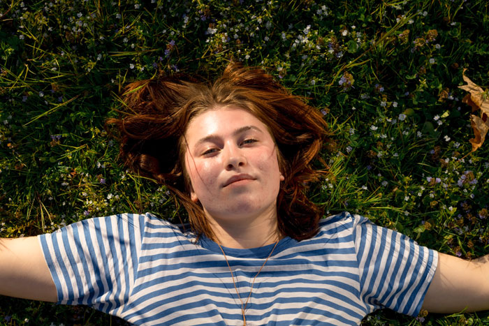 A woman with a striped shirt lying on the grass