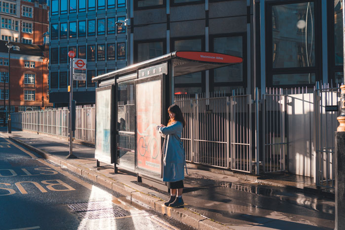 A woman waiting bus at the city bus stop