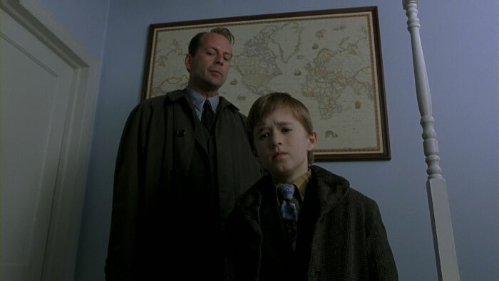 Two actors in dark coats standing indoors with a framed world map behind them, representing highest-paid actors.