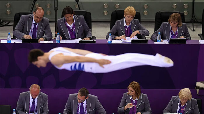 Two Rows Of Judges Ignore A Gymnast