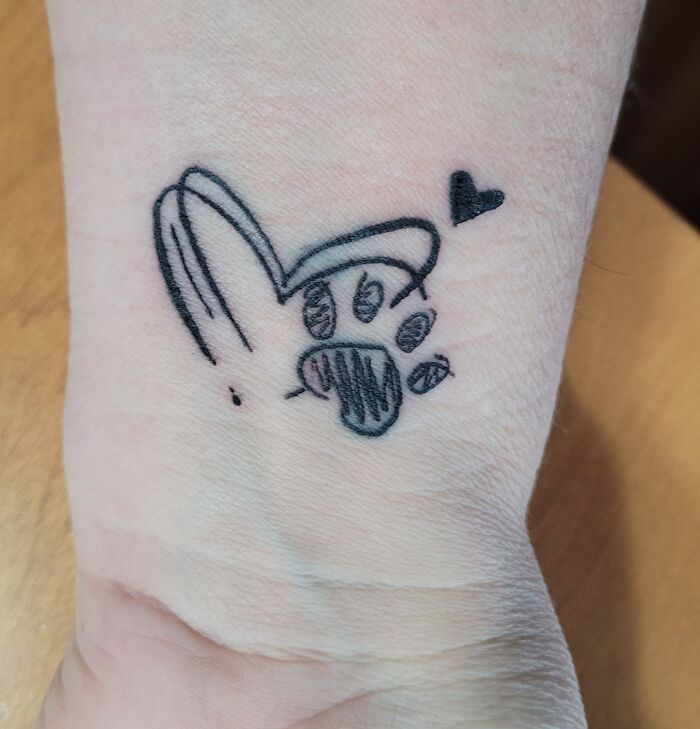 Tattoo on wrist with paw print and heart design.