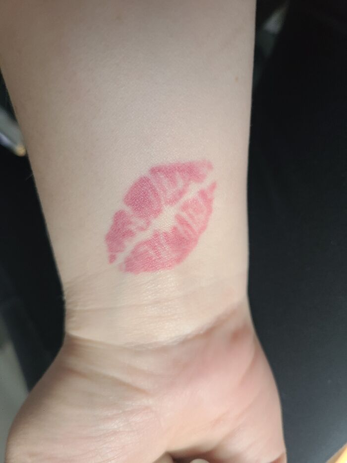 Kiss tattoo design on a person's wrist.