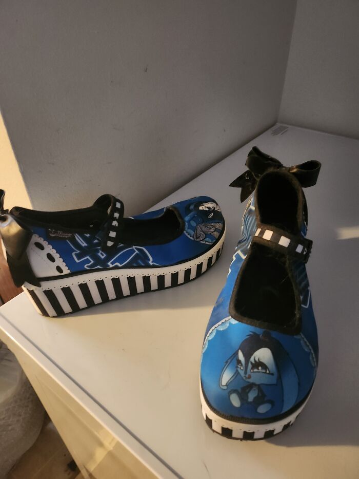 Unique blue shoes with a cartoon character design and striped platform soles, highlighting weird footwear style.