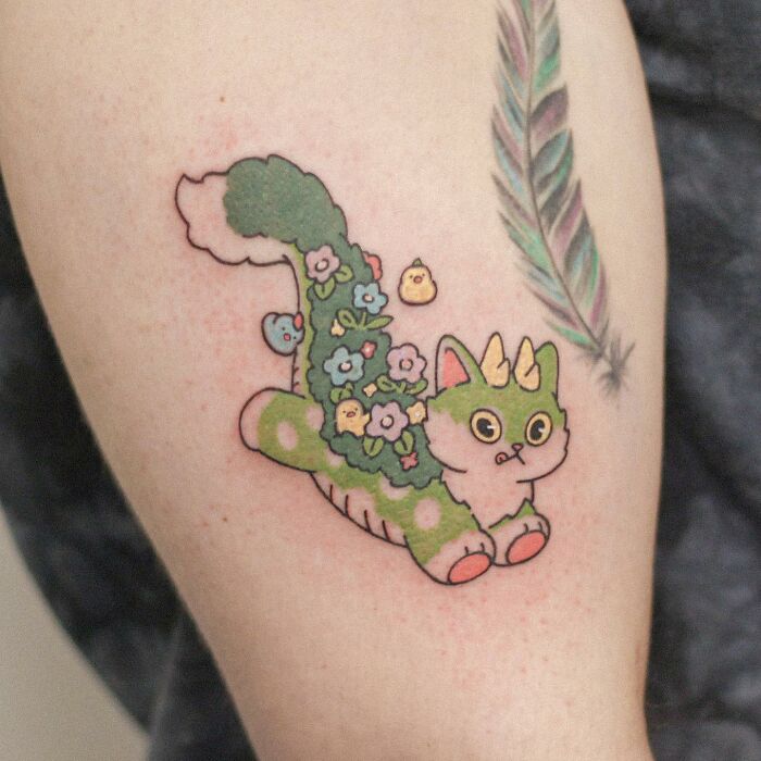 Adorable animal-themed tattoo of a mythical creature with flowers, situated on a person's arm.