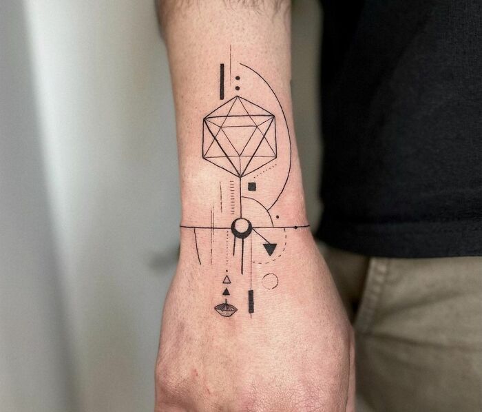 Geometric tattoo design on forearm featuring circles and lines in black ink.