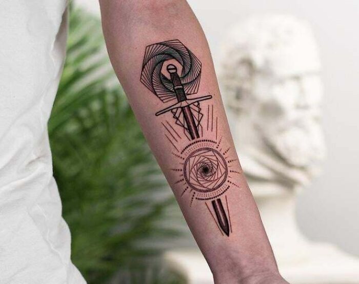 Geometric tattoo on forearm featuring a sword with circular patterns.