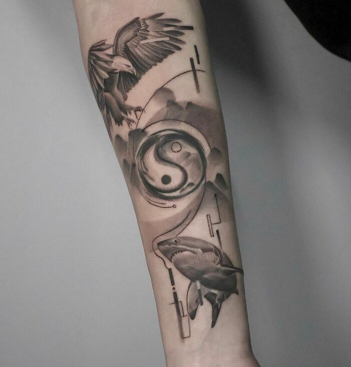 Geometric tattoo featuring a yin-yang symbol, eagle, and shark on an arm.
