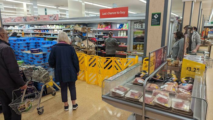 El supermercado local ha comenzado a poner una barrera protectora alrededor de los empleados mientras ponen la comida de precio reducido en los estantes. Fuera del encuadre de la foto hay una horda de pensionistas ansiosos lista para saltar