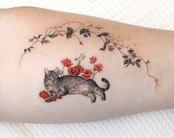 Realistic tattoo of a cat with floral design on arm, showcasing intricate and amazing details.