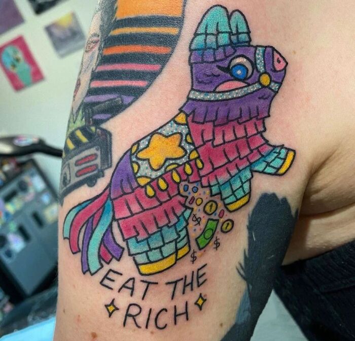 Colorful piñata tattoo with "Eat the Rich" design on an arm.