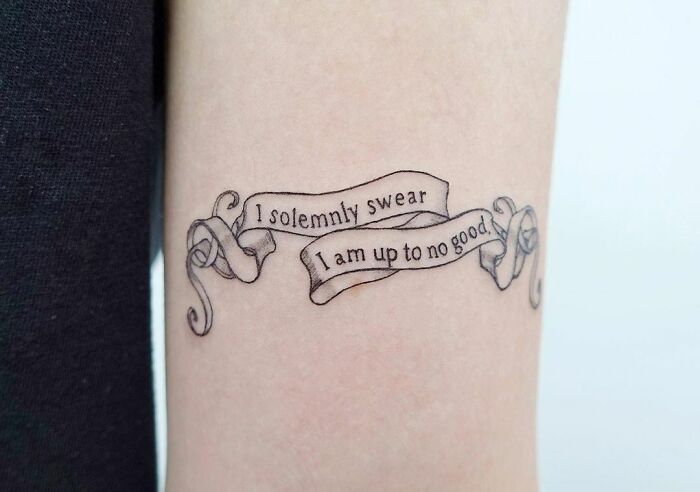Harry Potter tattoo with "I solemnly swear I am up to no good" quote on arm.