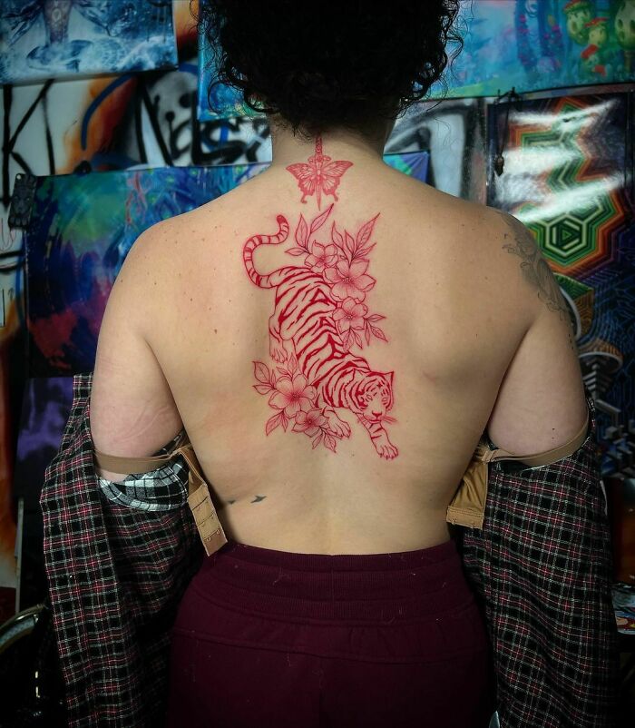 Red ink butterfly tattoo on the lower back