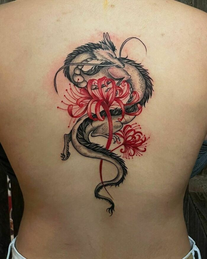 Red ink tattoo featuring a dragon entwined with red flowers on a person's back.