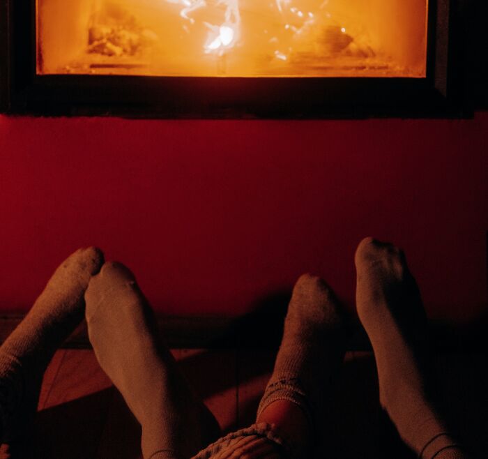 Couple Warming Their Feet Next To Fireplace